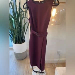 Sleeveless dress with belt and skirt has opening.